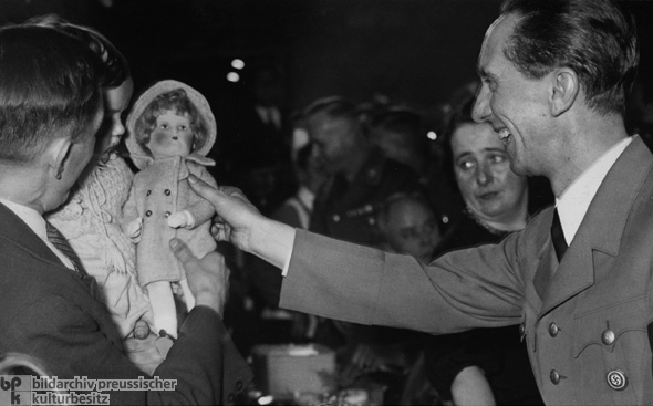 Joseph Goebbels Gives a Present to a Child during a Winter Relief Organization Event (December 1, 1936)